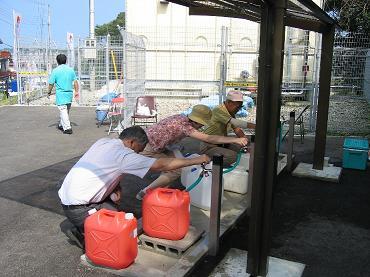 写真：温泉スタンドを利用して、温泉をポリ容器に入れているところ