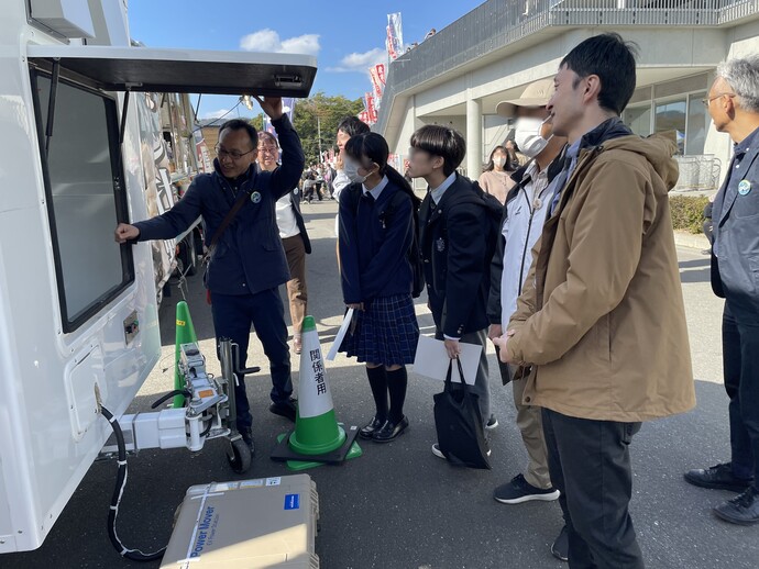 「EVが創る！ワクワク＆安心な暮らし」コーナー（屋外） バッテリキューブを説明している様子